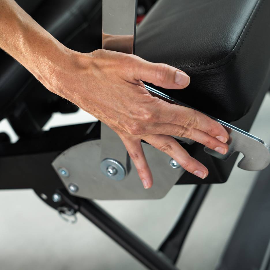 Hand verstelt een hendel op een zwarte fitnessbank.
