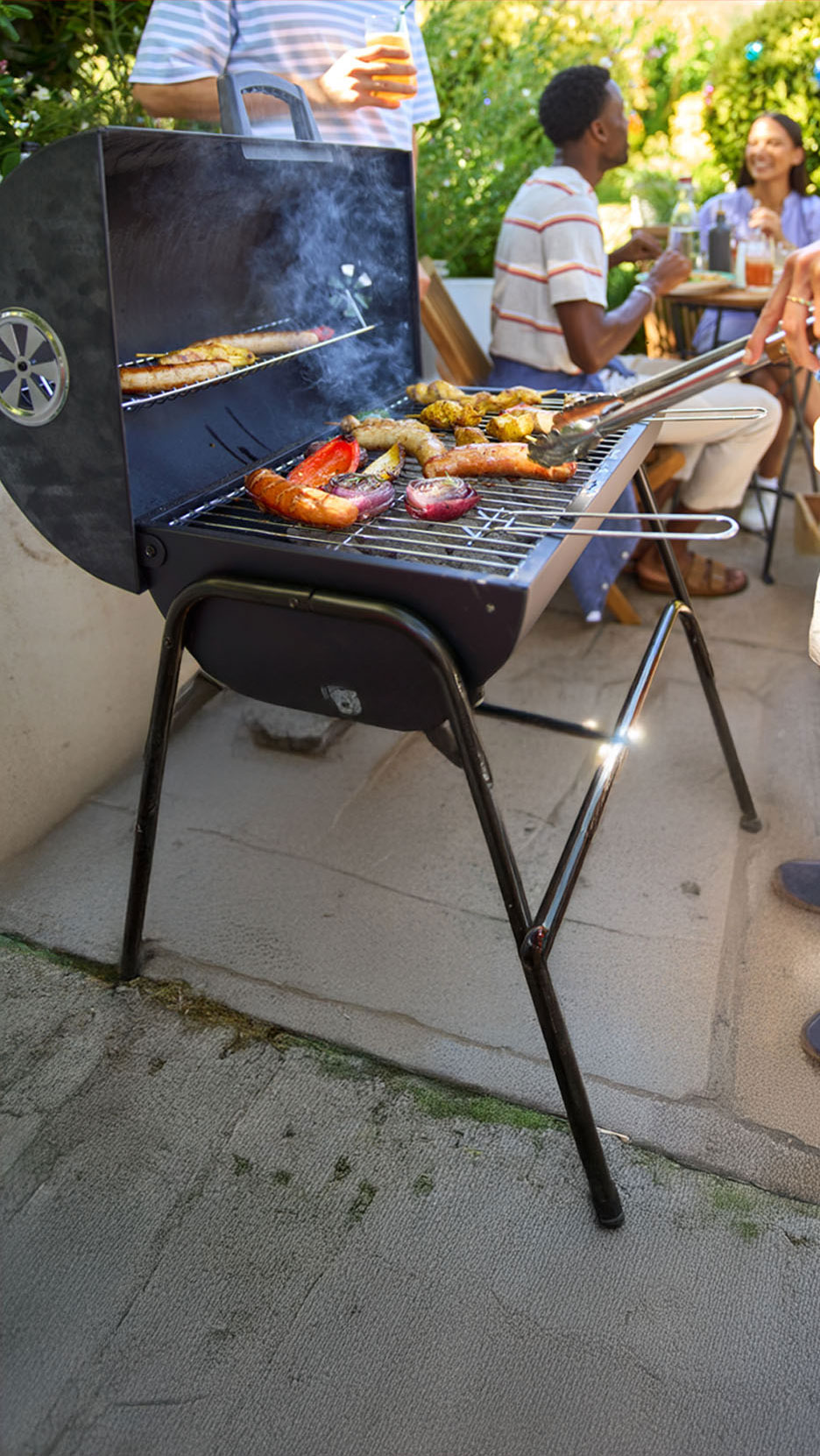 Een houtskoolbarbecue met worsten en gegrilde groenten.