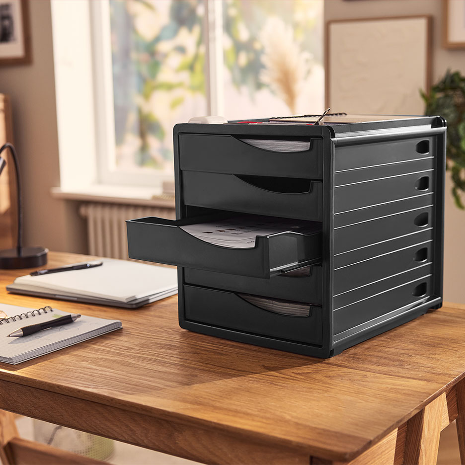 Zwarte bureau-organizer met lades, gevuld met papieren, op een houten tafel