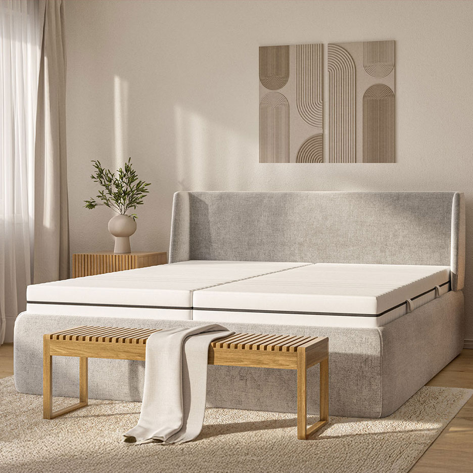 Slaapkamer met grijs bed, houten bankje, bijzettafel en wanddecoratie.
