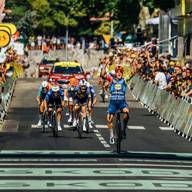 Cycliste franchit la ligne d'arrivée en vainqueur, d'autres cyclistes suivent.