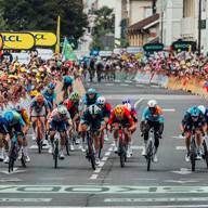 Cyclistes à vélo en course sur une route, avec une foule de fans en arrière-plan.
