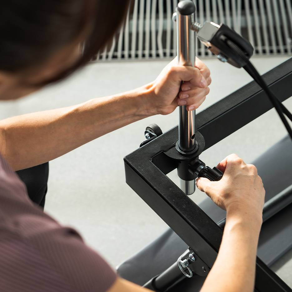 Persoon die fitnessapparatuur afstelt, focus op handen en metalen onderdelen.