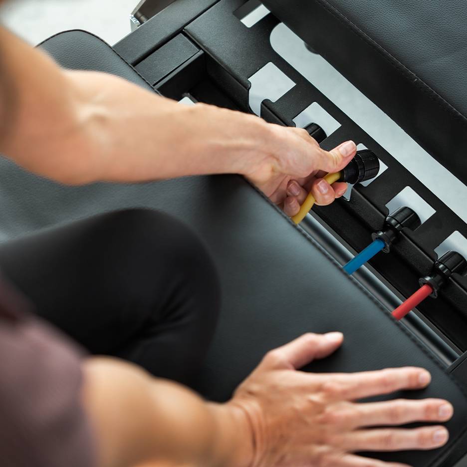 Persoon past weerstandsbanden aan op een fitnessbank.