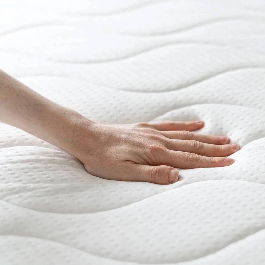 Hand drukt op een wit, zacht matras met golvende stiksels.