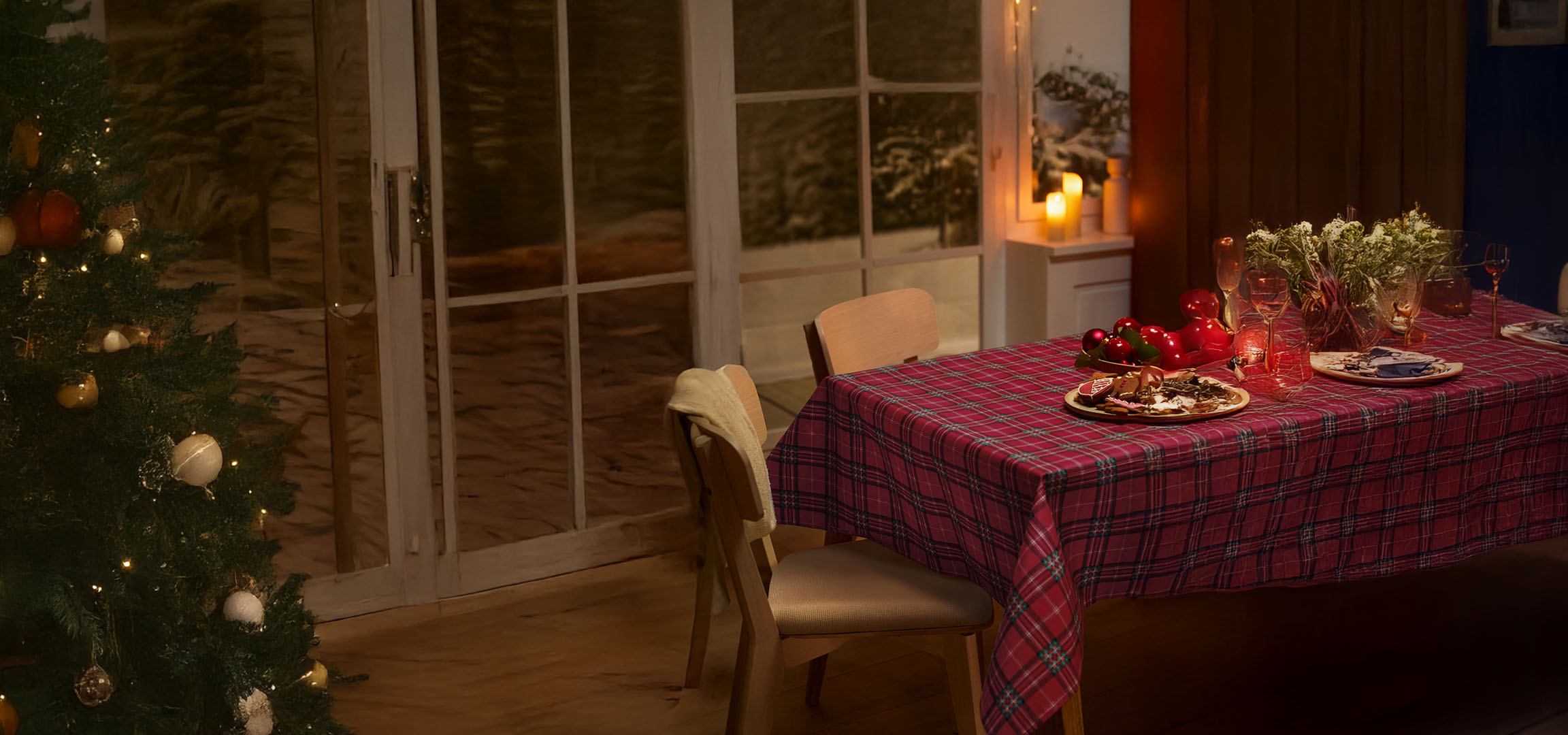 Kerstboom en feestelijk gedekte tafel met geruit tafelkleed, peperkoek en kerstdecoraties.