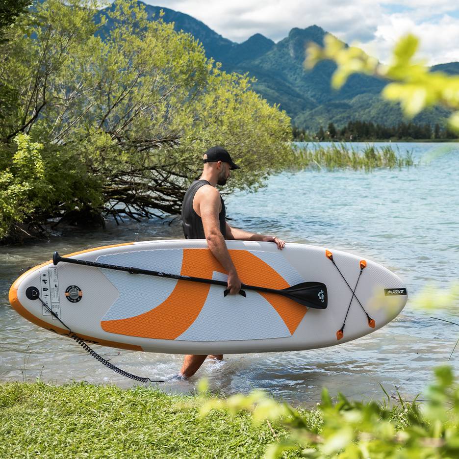 Man met CRIVIT paddleboard in het water, klaar om te peddelen.