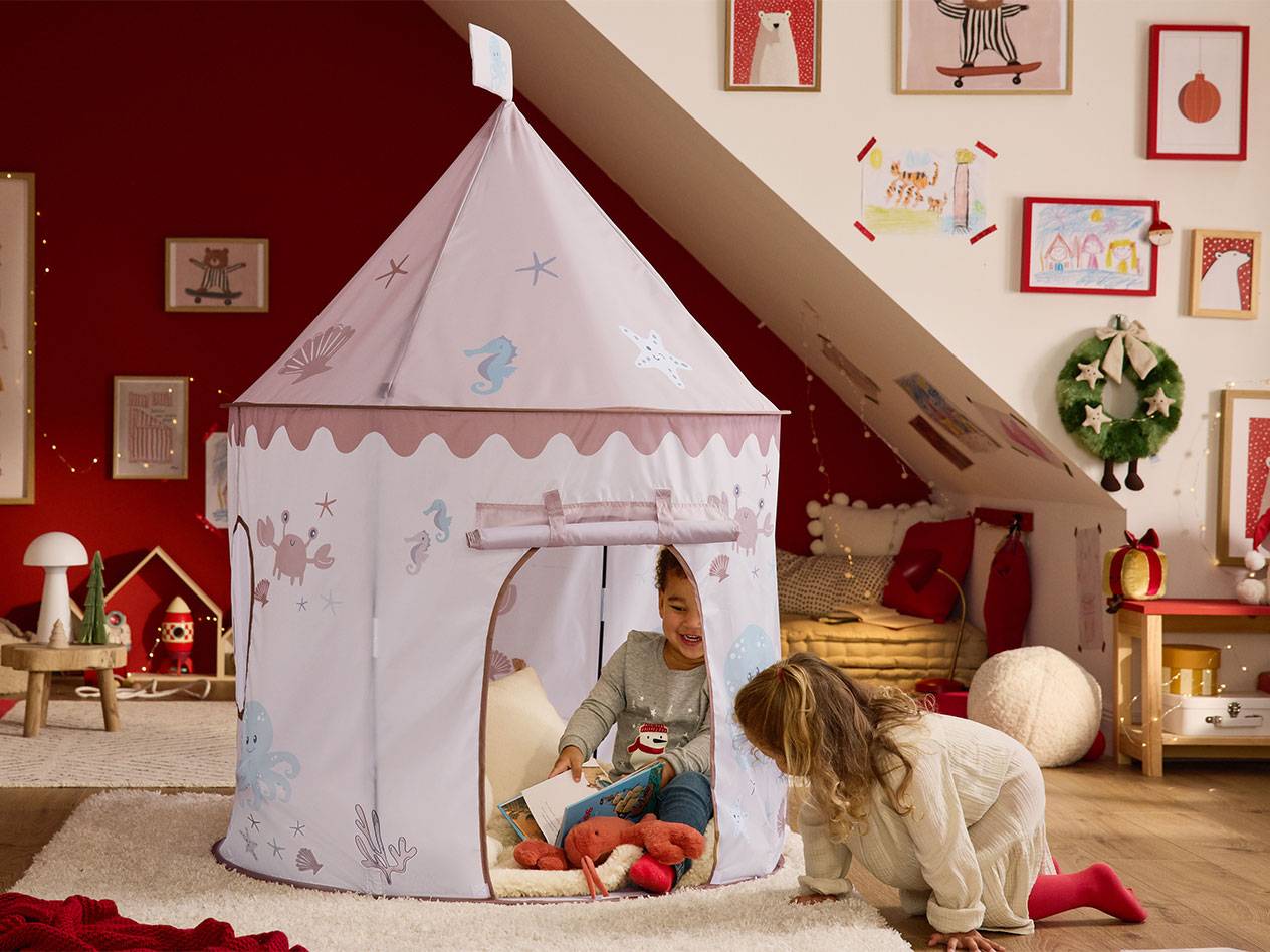 Twee kinderen spelen met een speeltent met zeethema in een kinderkamer met kerstversiering.