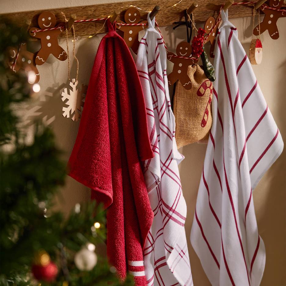 Rode en witte kerstkeukenhanddoeken hangend aan een houten rek met peperkoekdecoraties.