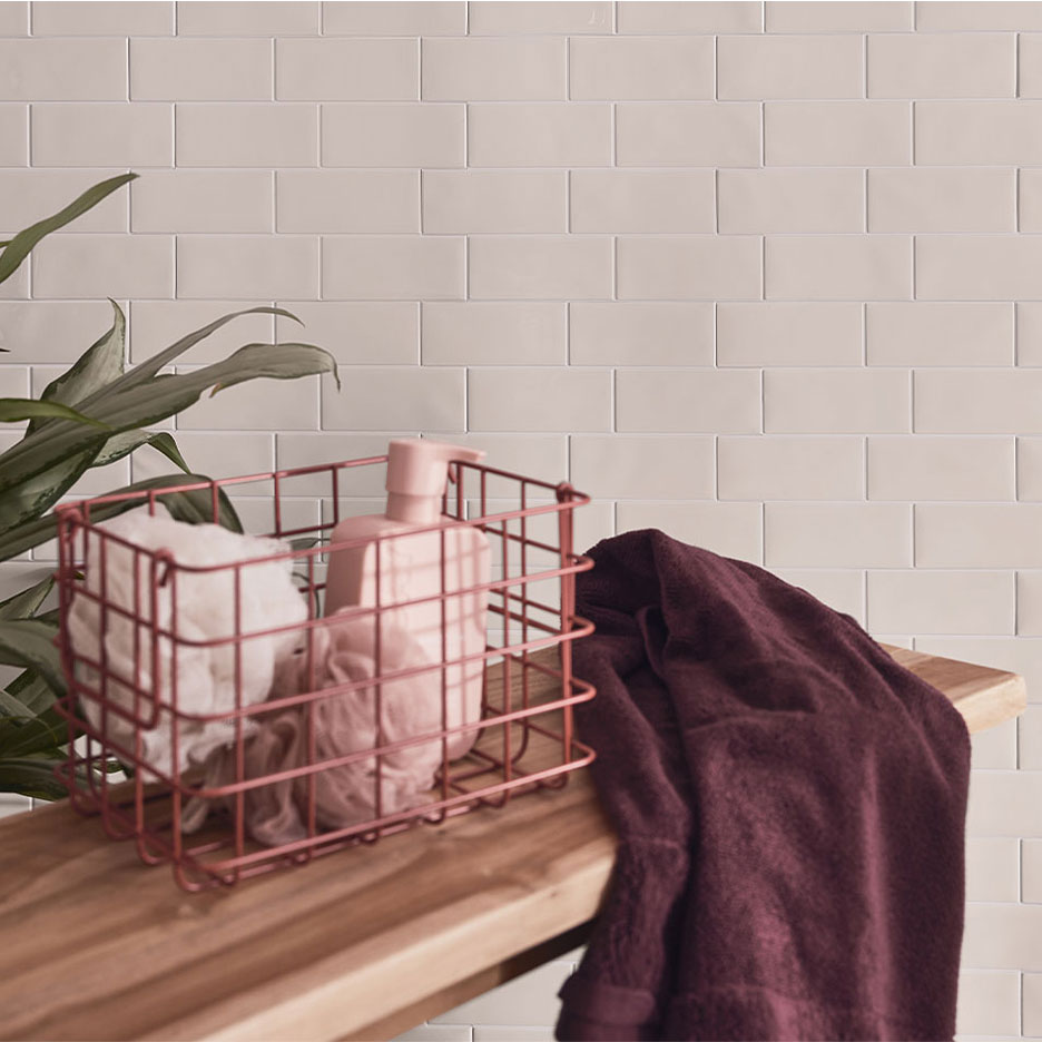 Badkamerdecoratie met witte tegels, houten bank, mand met zeep en handdoeken.