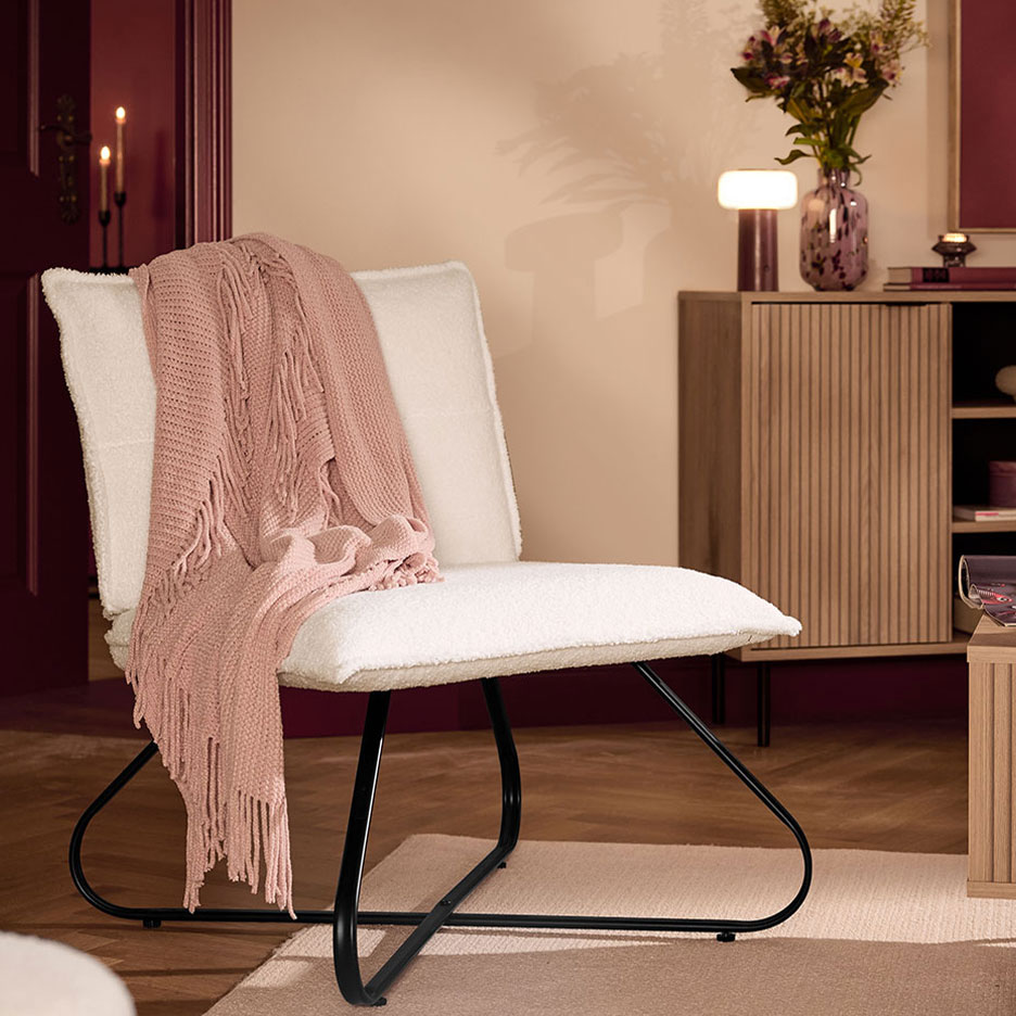 Een witte fauteuil met een roze deken in een gezellige woonkamer.