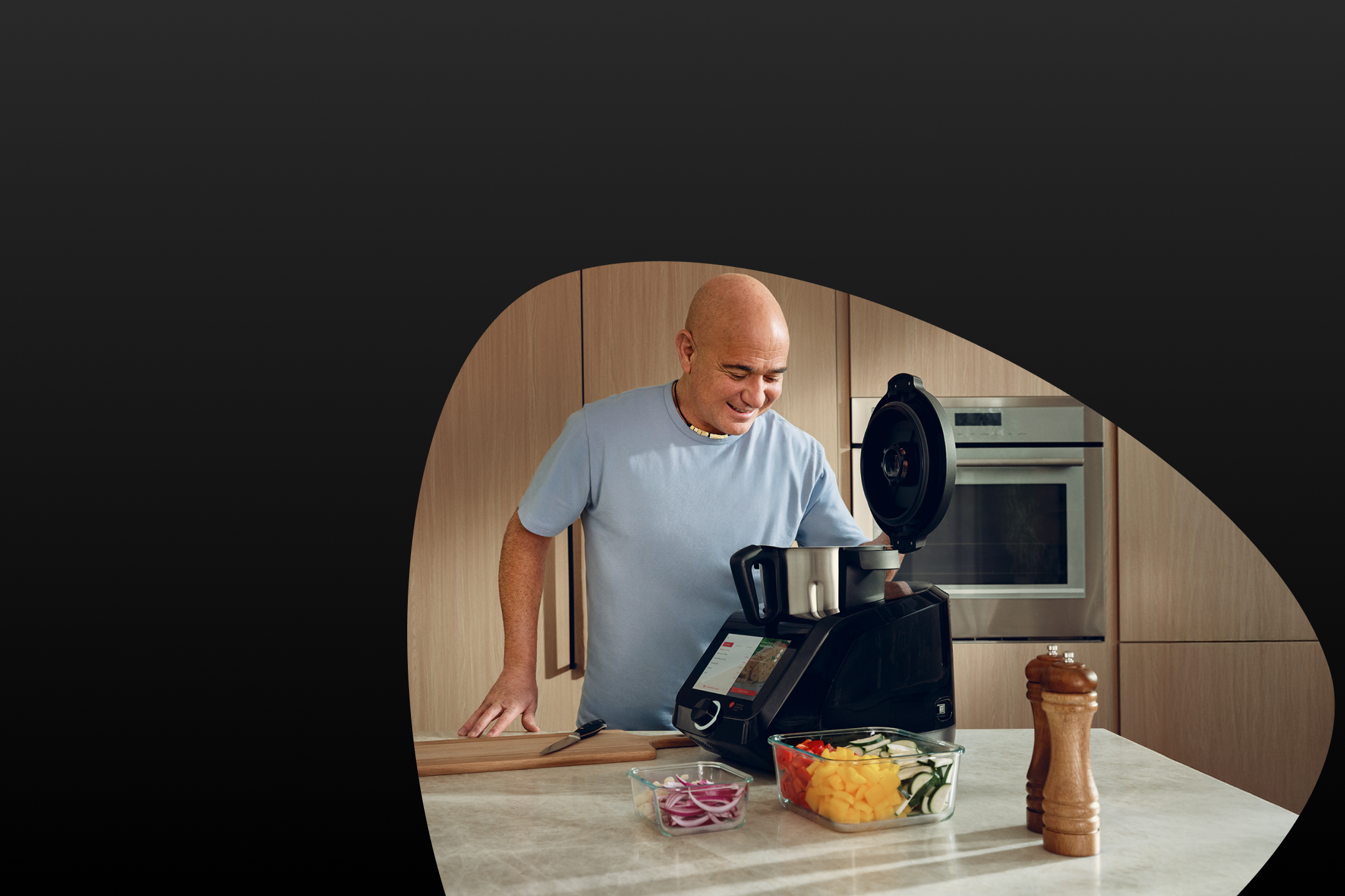 Man kookt in een keuken met een keukenmachine en gesneden groenten.