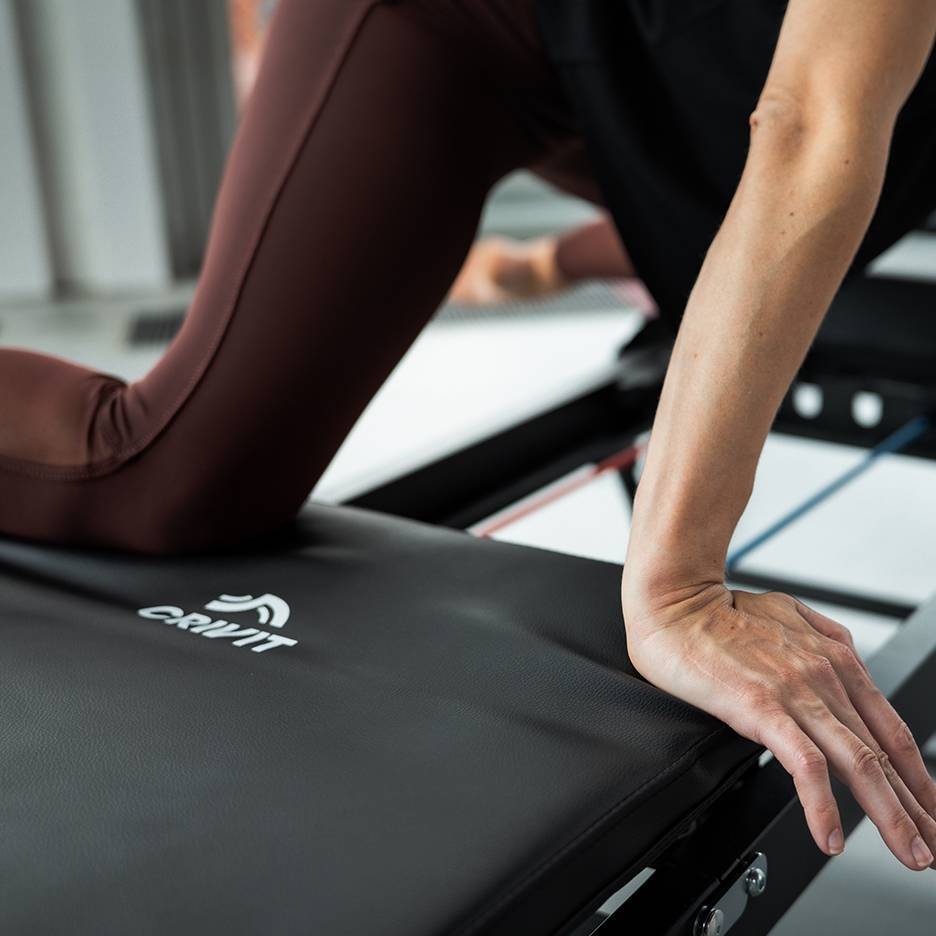 Vrouw traint op een Crivit fitnessapparaat in een bruine yogabroek.