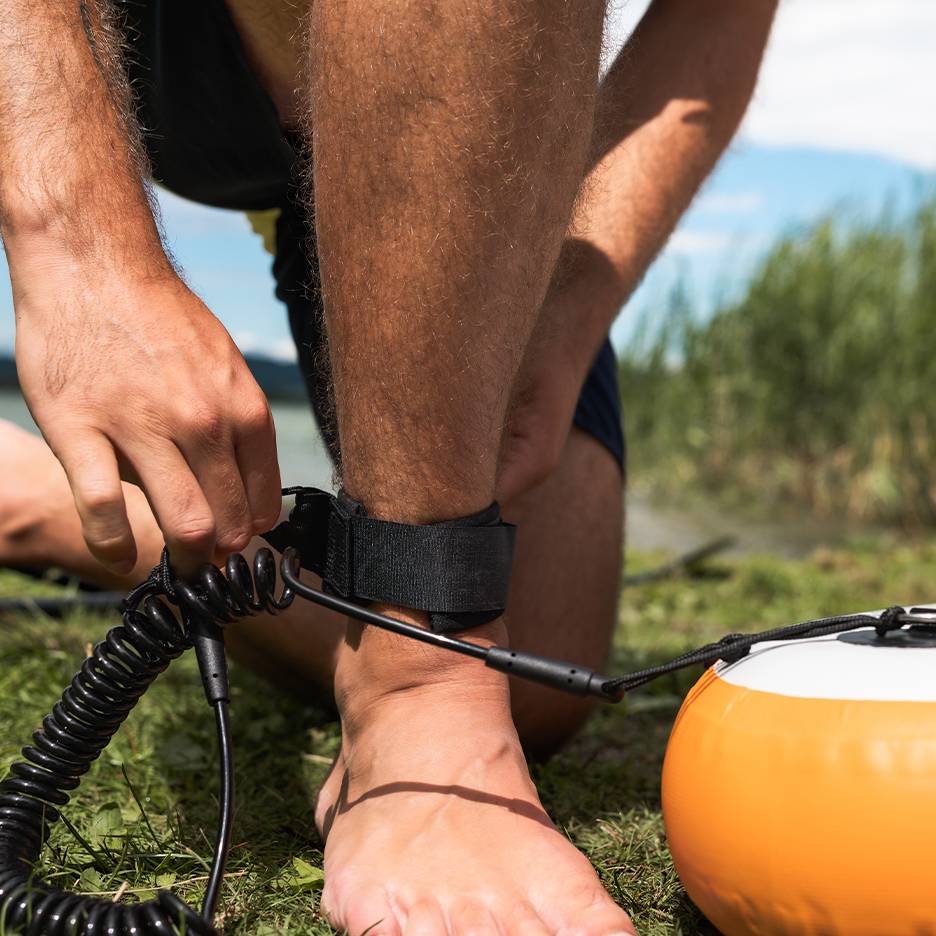 Man bevestigt paddleboard-leash aan zijn enkel.