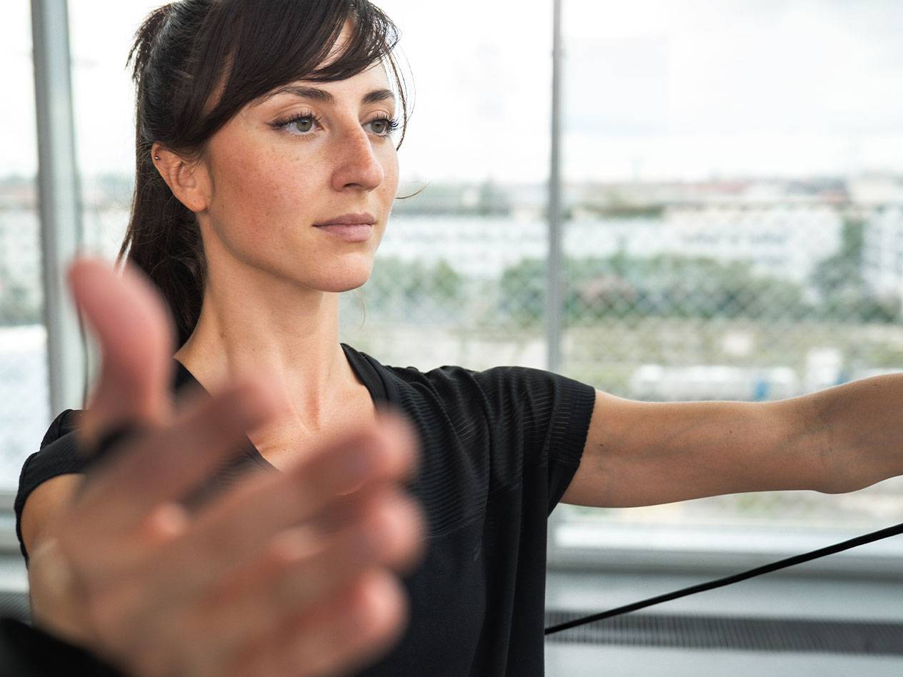 Vrouw traint met een weerstandsband voor een raam.