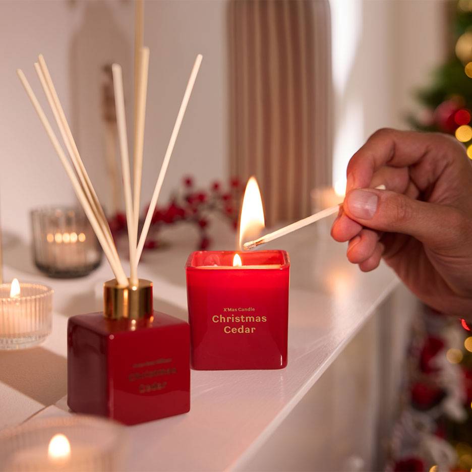 Rode kerst ceder diffuser en kaars worden aangestoken met een lucifer.