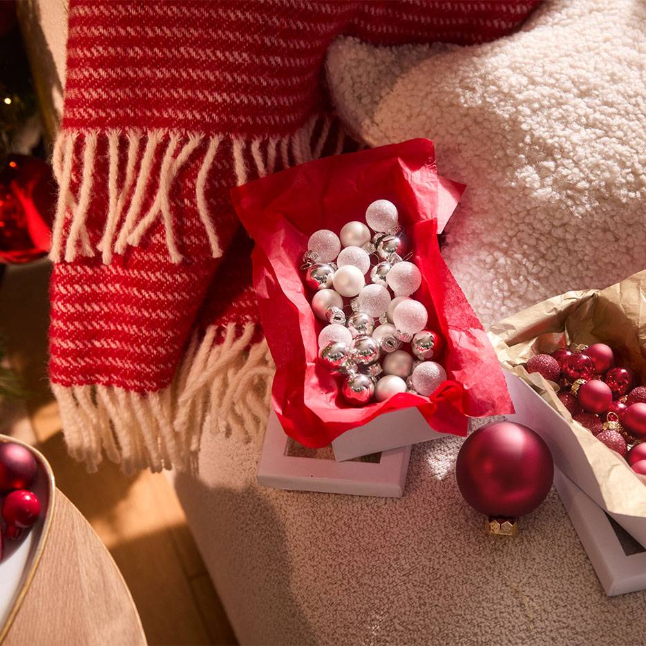 Kerstdecoraties: rode en zilveren ballen in dozen, met een deken en kussen.