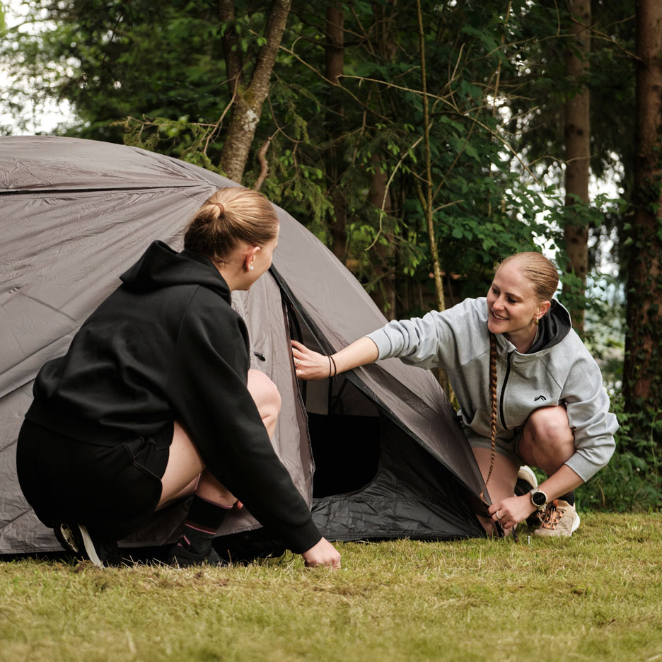 Twee vrouwen zetten een tent op in het bos.