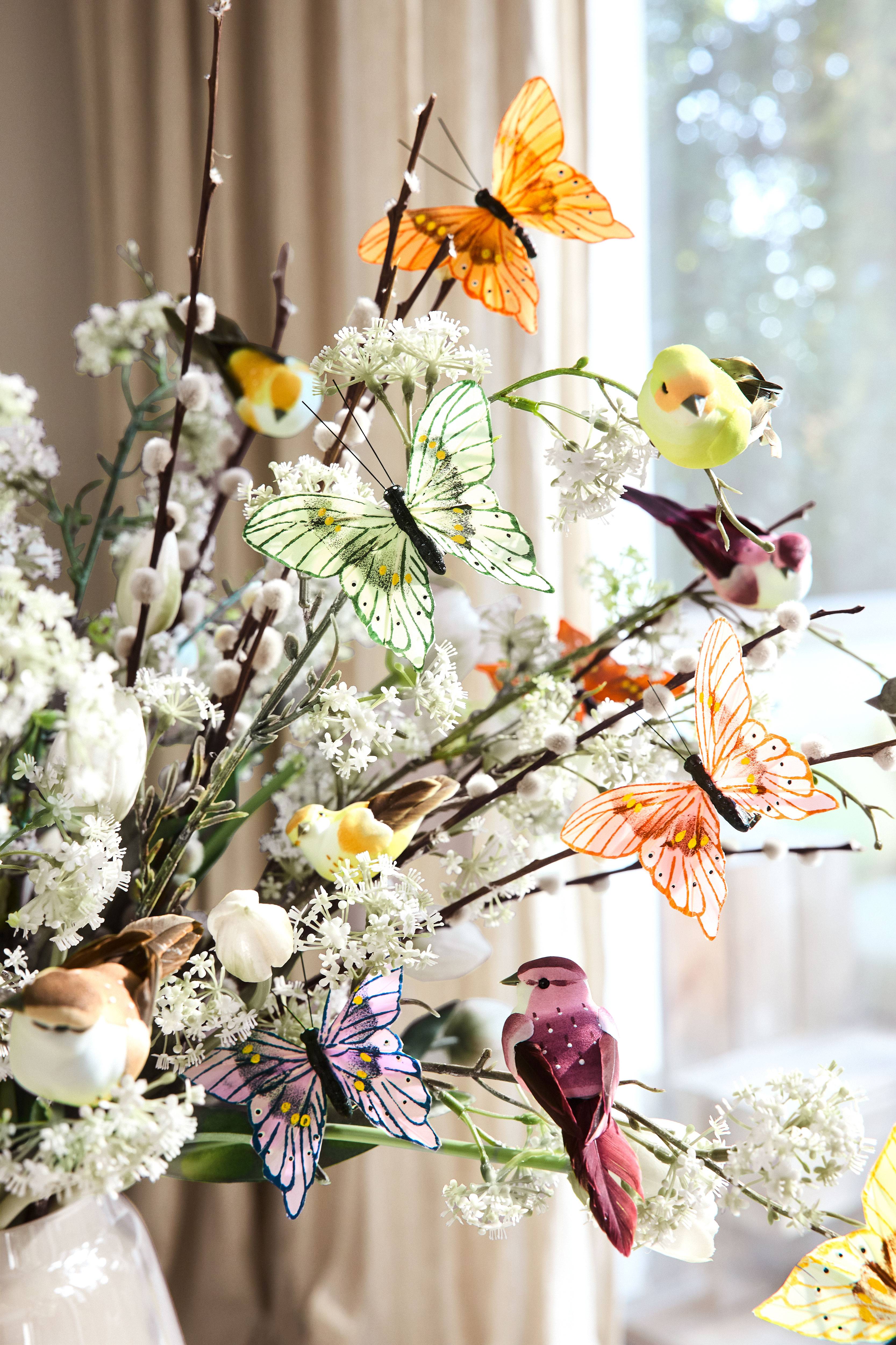 Lentedecoratie met kunstvlinders, vogels en bloemen in een witte vaas.