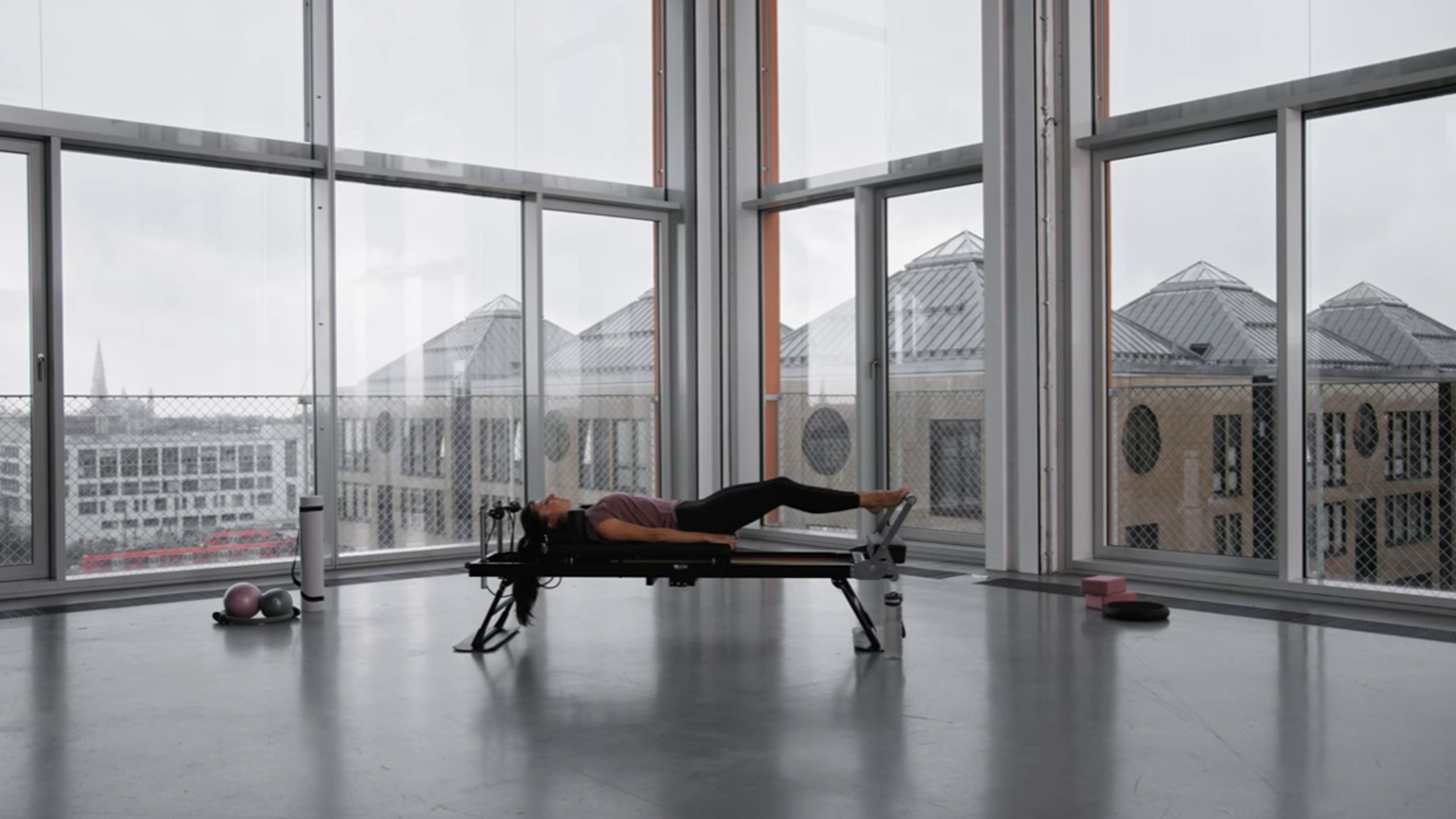Vrouw doet Pilates in moderne studio met uitzicht op de stad.