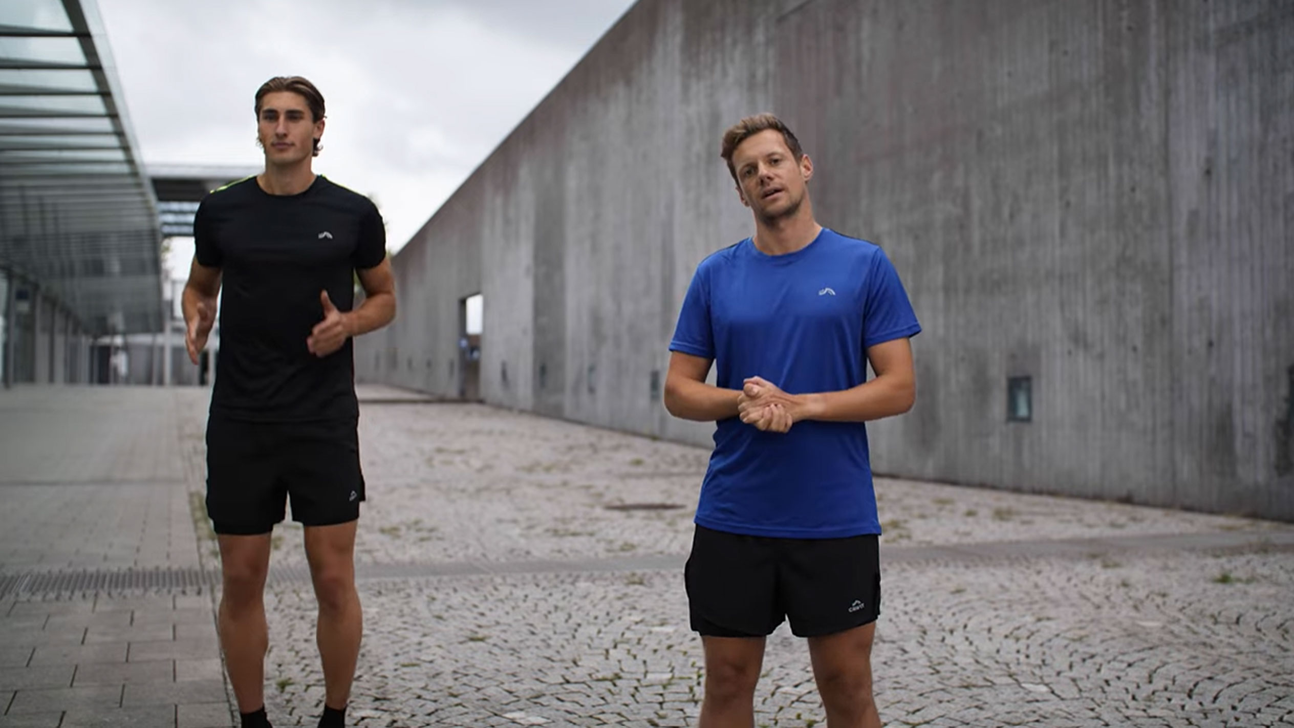 Deux hommes en tenue de sport noire et bleue à l'extérieur.