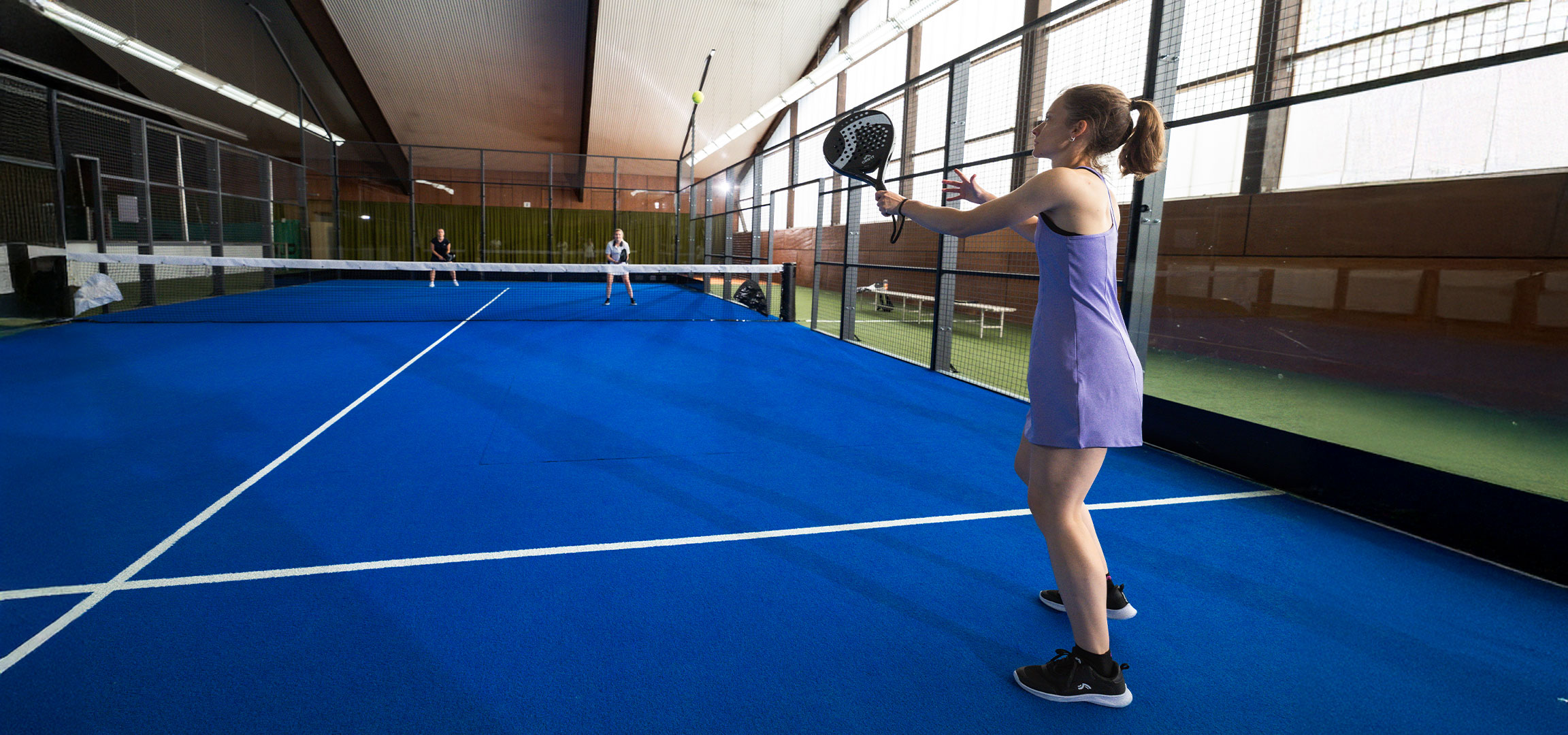 Lana Büttner speelt padel op de baan met een Crivit racket, een gele bal en andere spelers.
