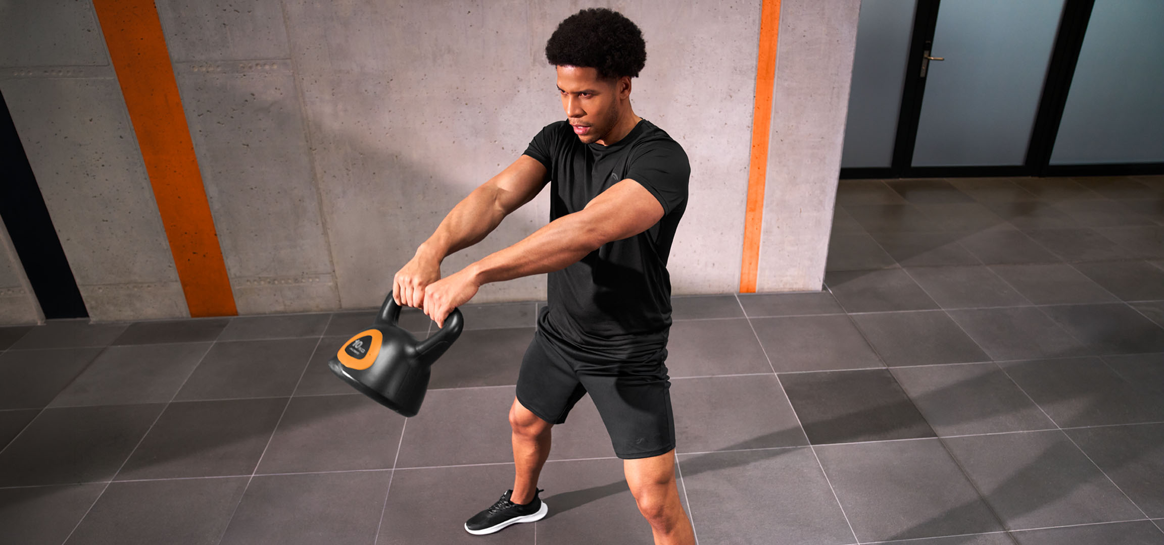 Gegenereerd door AI: Man traint met een zwart-oranje kettlebell.