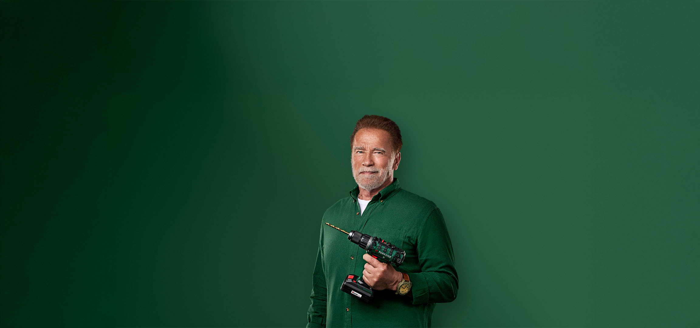 Arnold Schwarzenegger met een Parkside boormachine op een groene achtergrond.