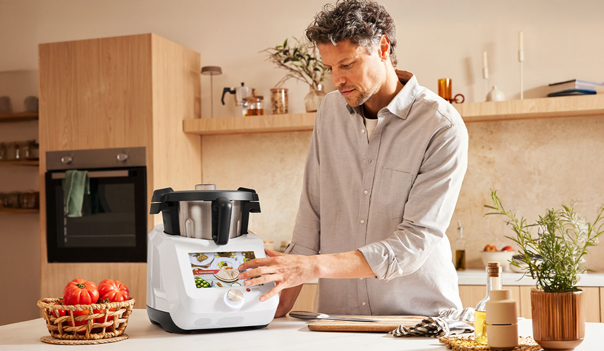 Un homme utilise un robot de cuisine Monsieur Cuisine dans une cuisine moderne.
