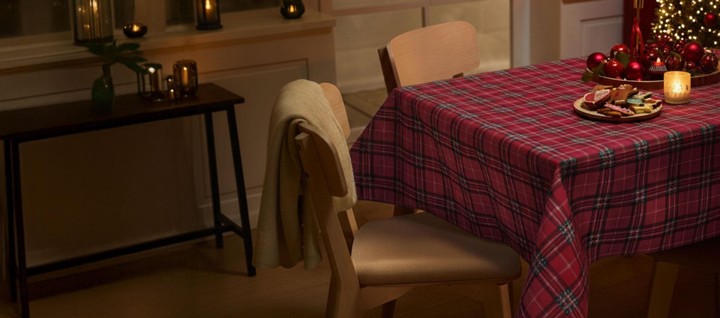 Table de Noël avec nappe à carreaux rouges, chaises et biscuits de Noël.