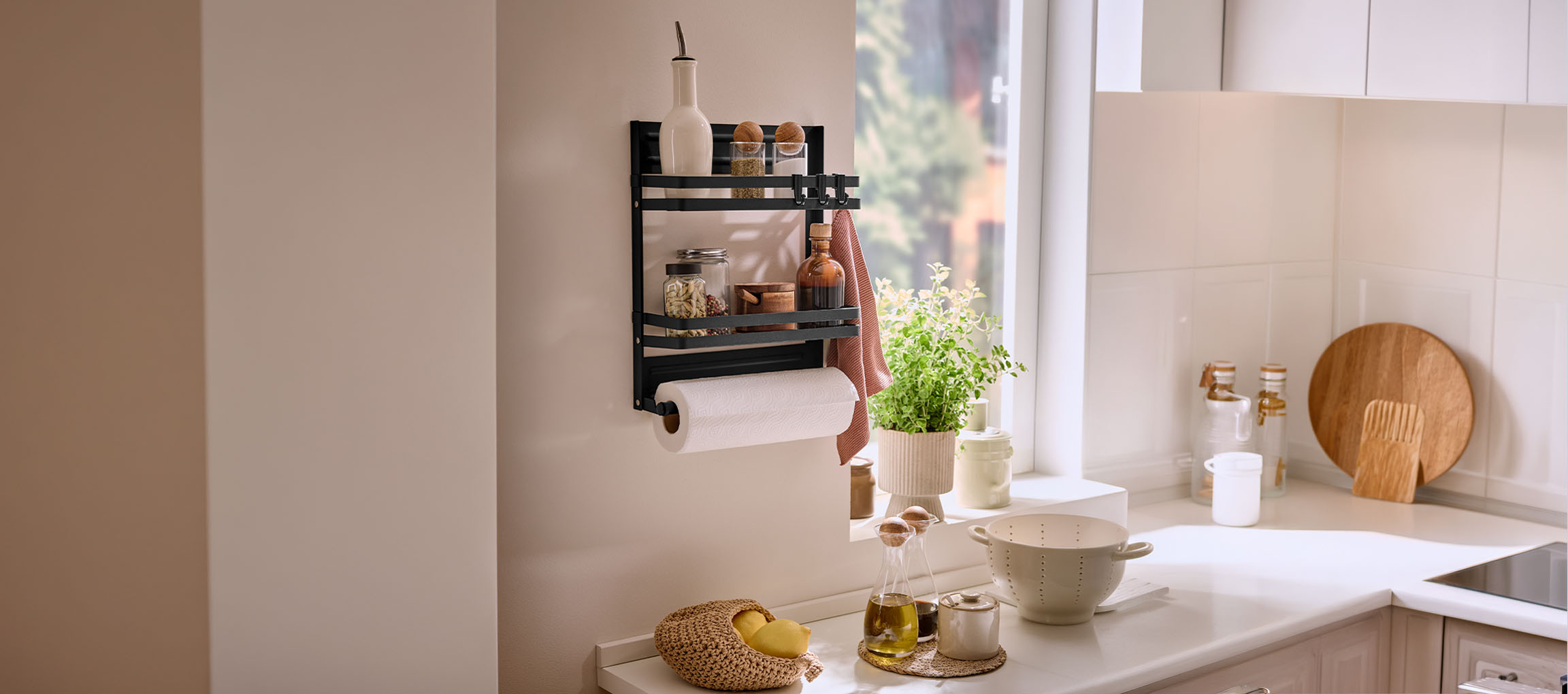 Étagère à épices murale noire avec porte-serviettes en papier dans une cuisine lumineuse.
