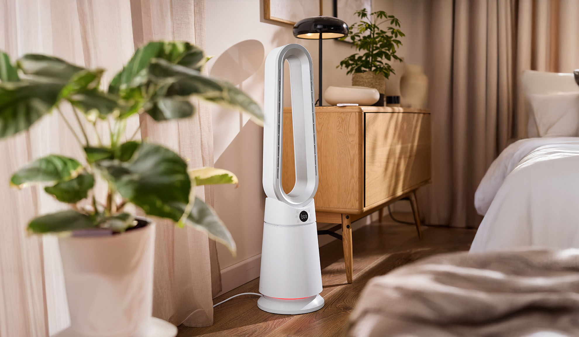 Witte torenventilator in een moderne slaapkamer met planten en houten meubels.