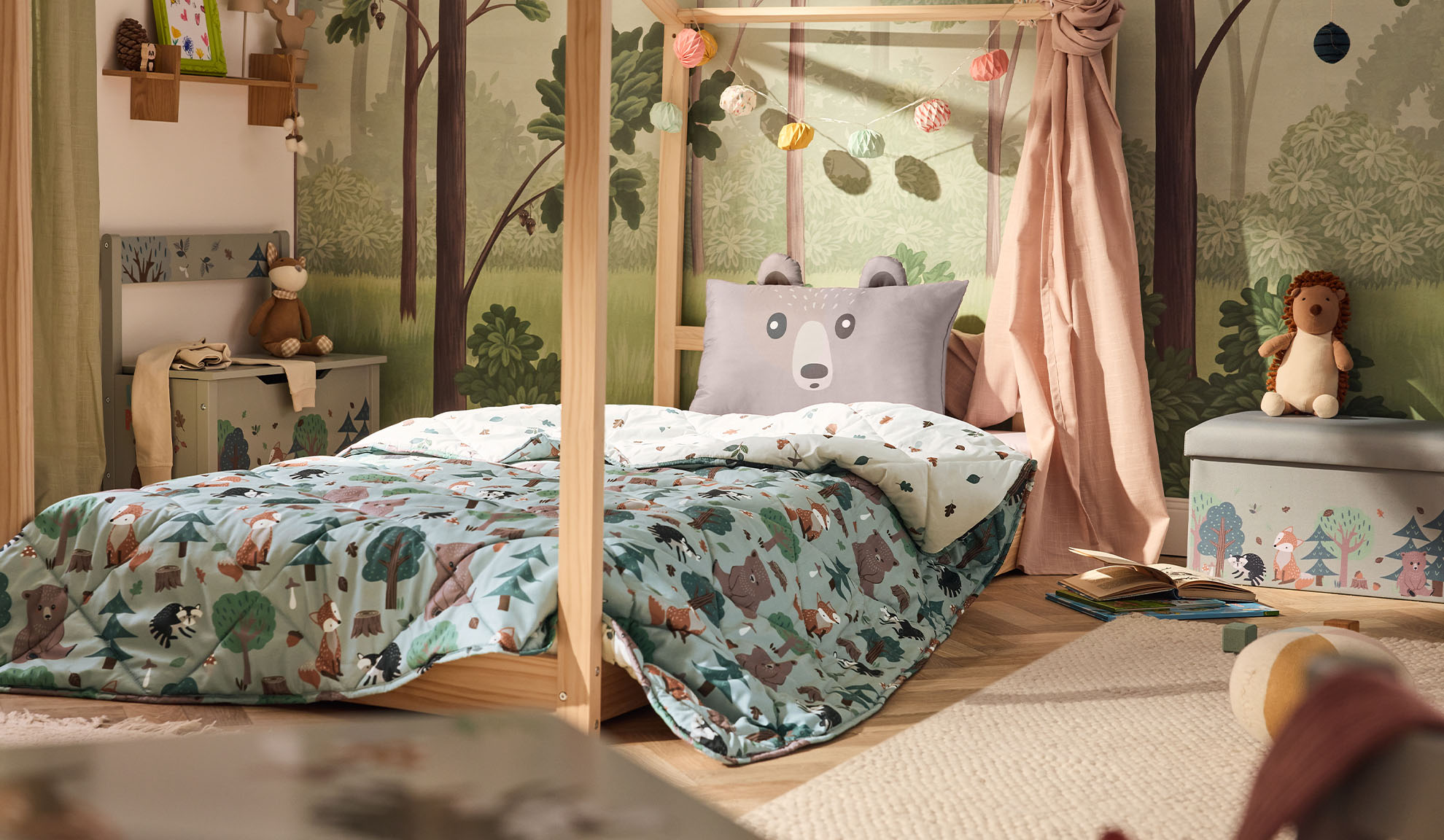 Chambre d'enfant avec lit en bois, oreiller ours et couette à motif forestier.