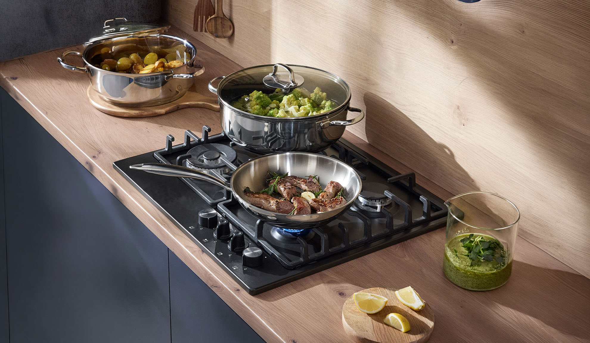 Table de cuisson à gaz avec une poêle et des casseroles sur un comptoir en bois, préparant un repas.