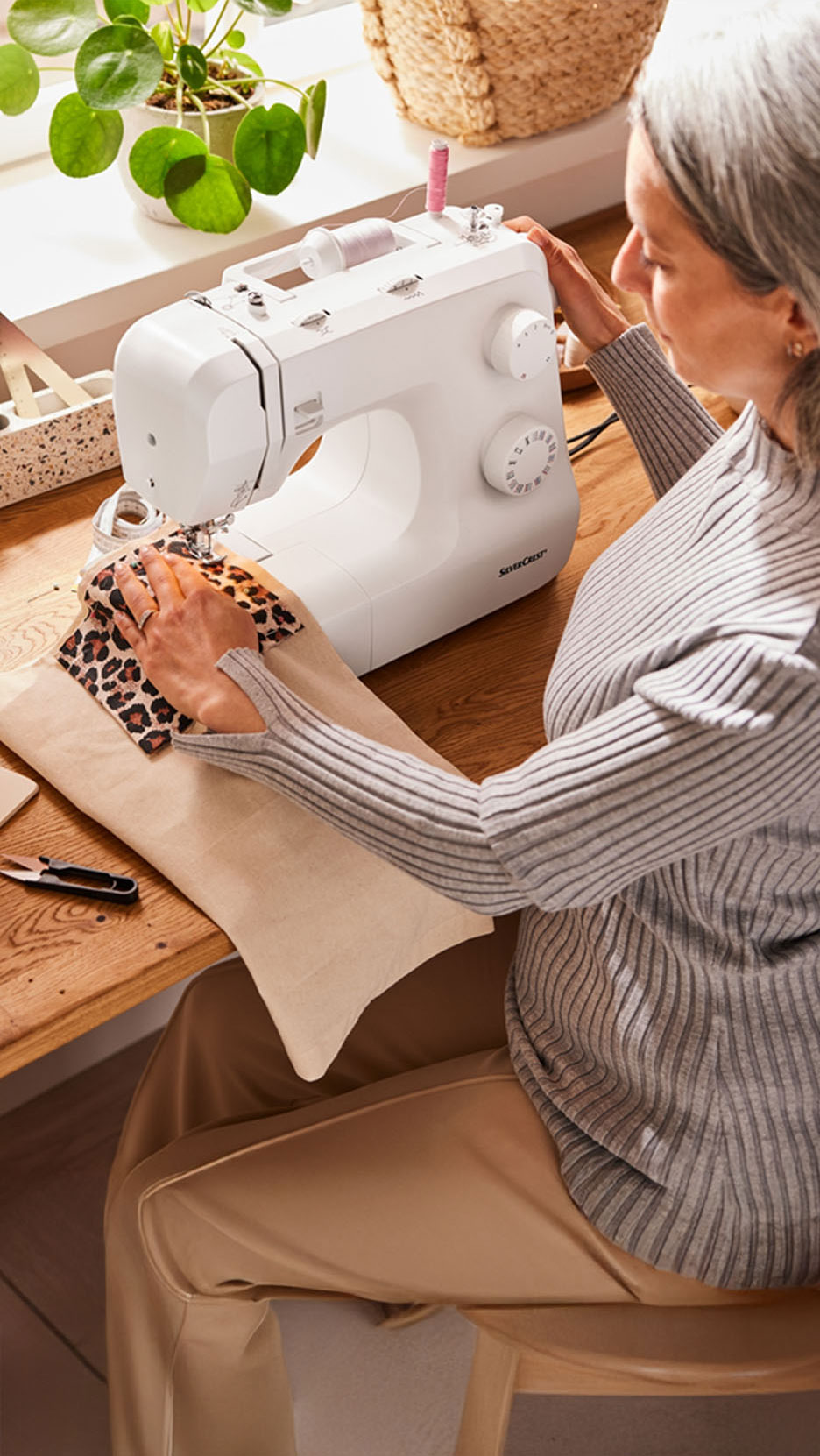 Een vrouw naait luipaardprint stof op een Silvercrest naaimachine.