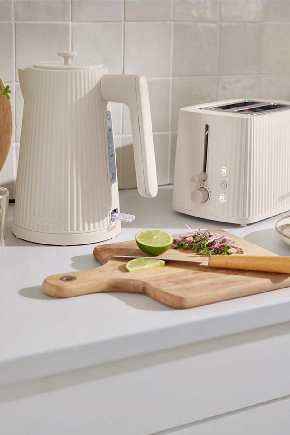 Crèmekleurige waterkoker en broodrooster op een aanrecht.