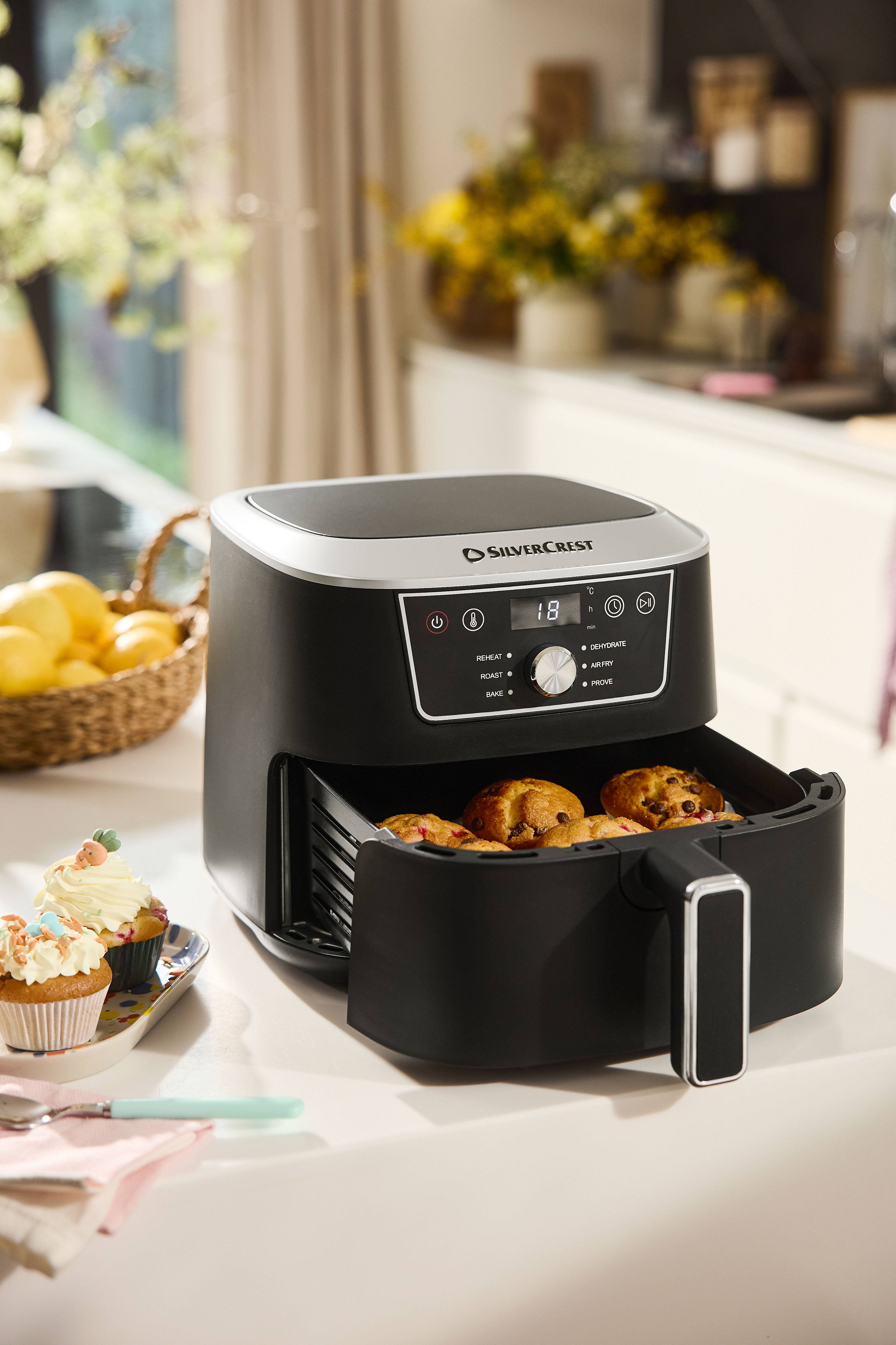 Zwarte Silvercrest heteluchtfriteuse met open lade vol muffins op een aanrecht.