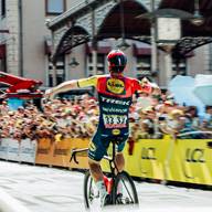 Cycliste célèbre sa victoire devant la foule, portant un maillot jaune et rouge.