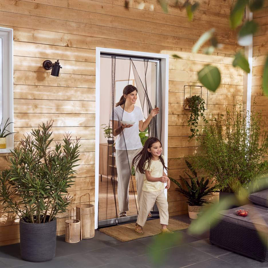 Vrouw en meisje stappen terras op met planten door een insectenhor.