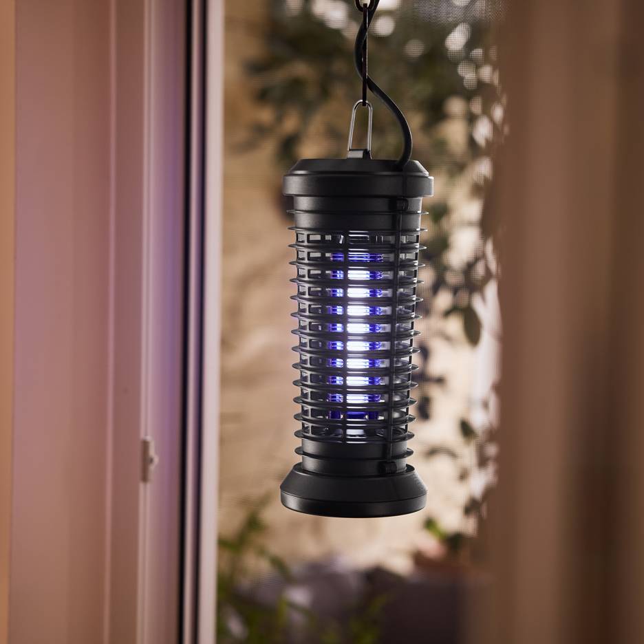 Elektrische insectenval met blauw licht hangend bij een raam.