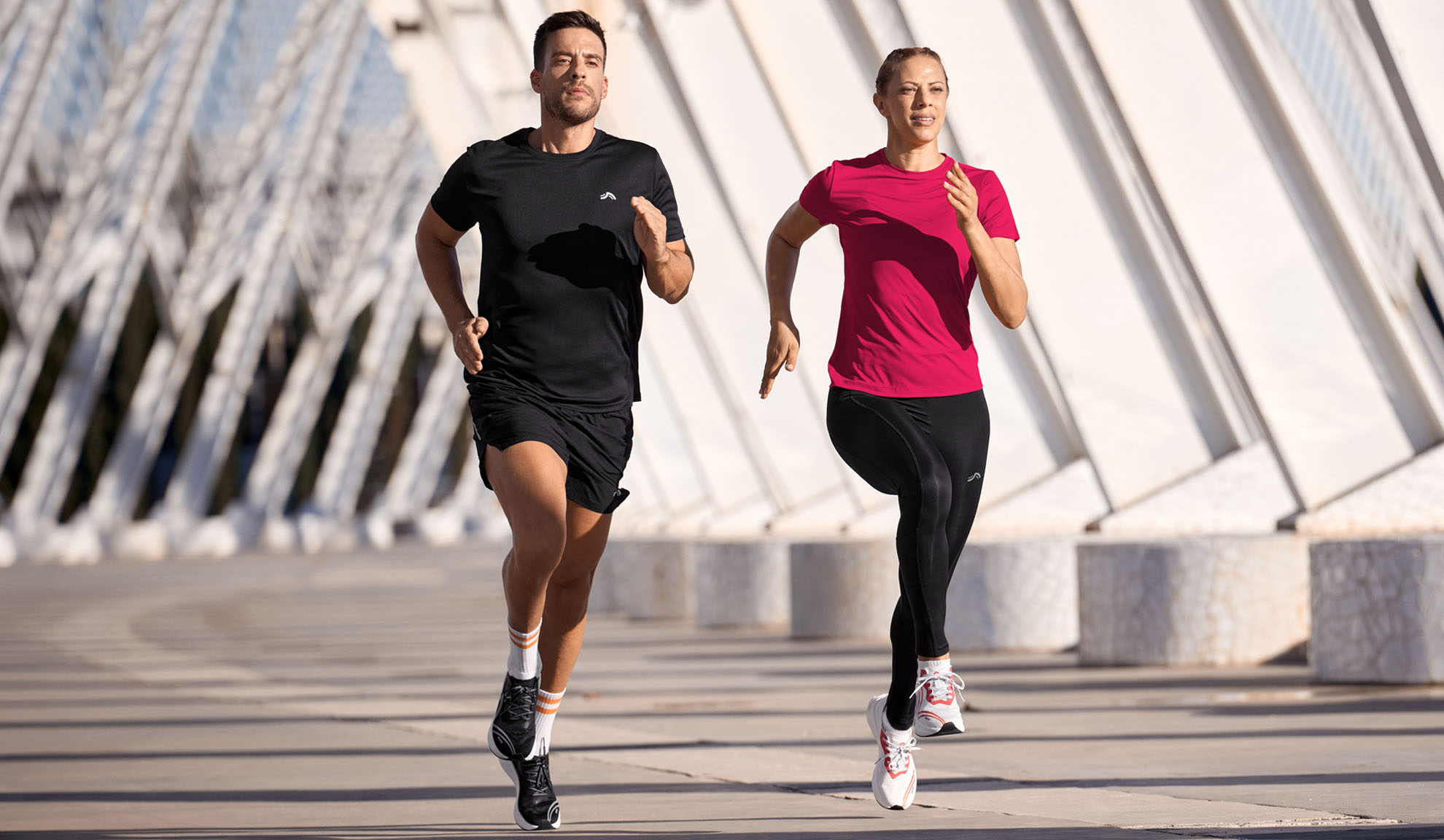 Homme et femme courant en tenue de sport, t-shirts et leggings.