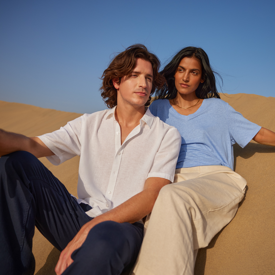 Twee jonge mensen in de woestijn, met een wit overhemd en blauw T-shirt, marineblauwe en beige broek.