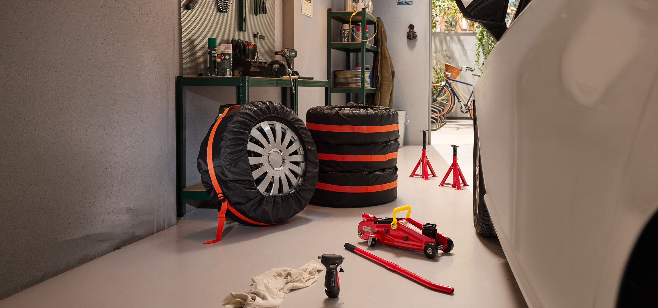 Winterbanden opgeslagen in een garage met een hydraulische krik en assteunen.