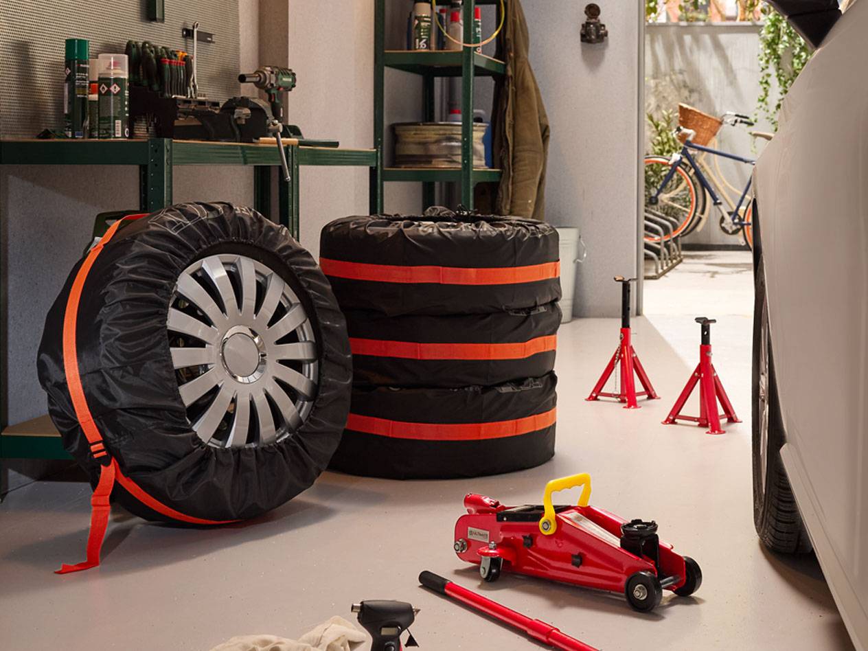 Winterbanden verpakt met hoezen, hydraulische krikken en autostandaards in een garage.