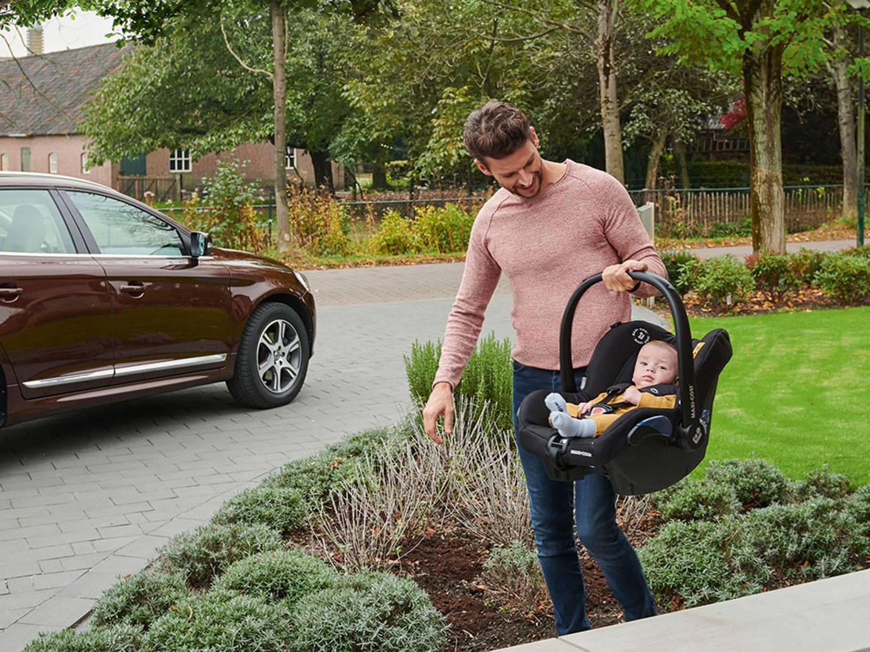 Vader draagt een Maxi-Cosi baby autostoeltje.