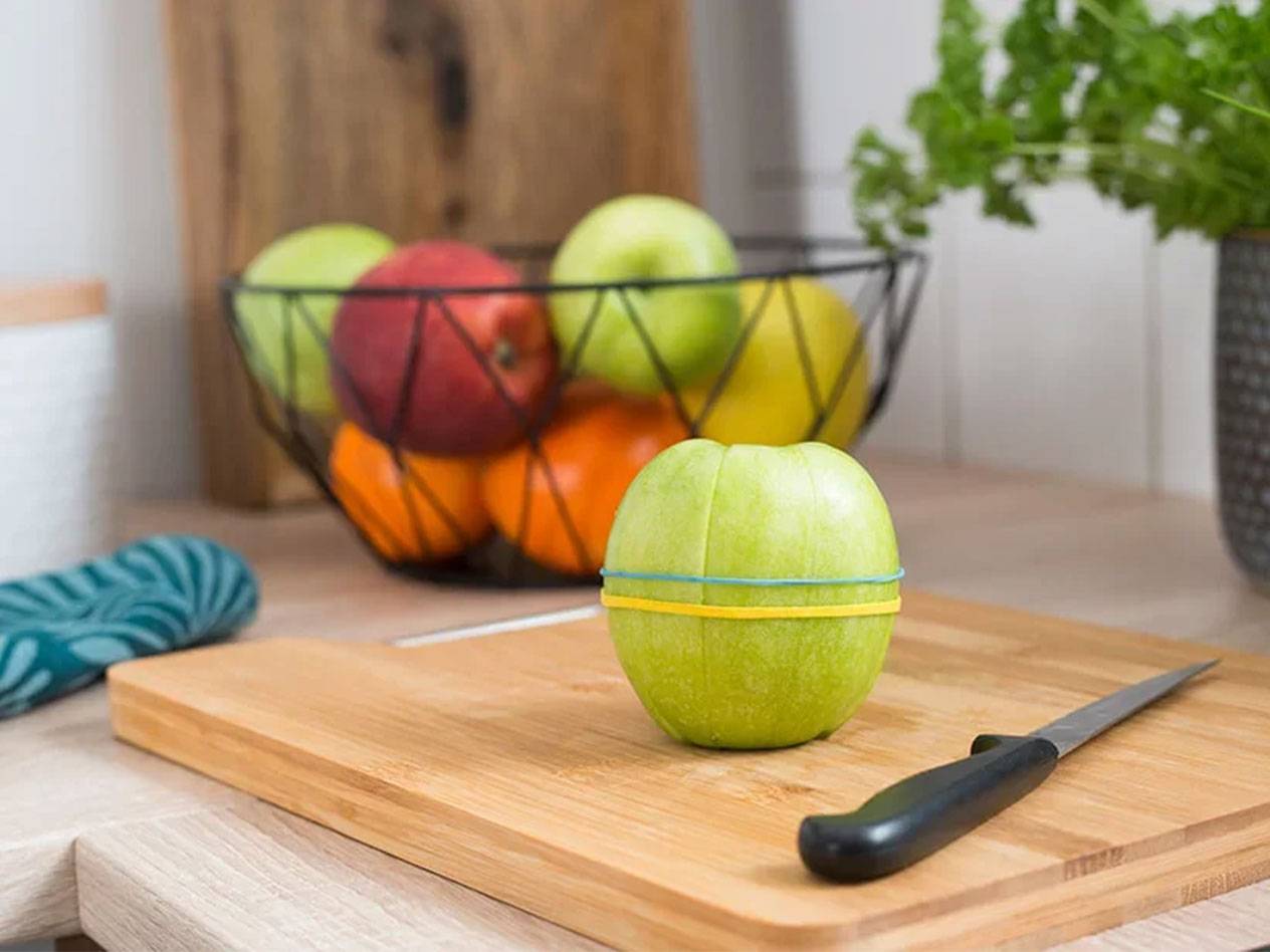 Pomme attachée avec des élastiques sur une planche en bois.